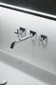 Chromene Wand-Waschtischarmatur mit zwei Kreuzgriffen, montiert an einer weißen Wand. Ideal Standard logo sichtbar.